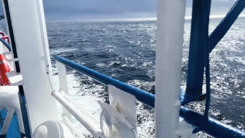 View from a boat deck showing railing and ocean wake Stockbeeldmateriaal 347825704