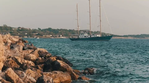 View of a boat floating on the blue-green sea with white sand many rock on the Stock Footage 107789181