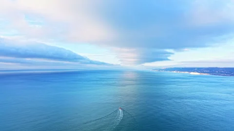 View of a boat navigating through calm waters of the ocean under a cloudy sky Stock Footage 336494905