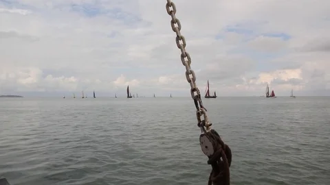 View from boat showing chain in foreground and sea with sailing ships Stock Footage 70092970