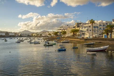 View of boats on beach in Baha de Arrecife Marina surrounded by shops, bars and Stock Photos