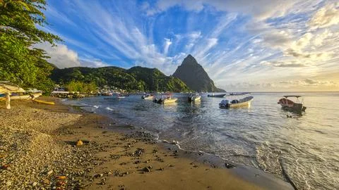 View of boats on the beach with the Pitons in the background during sunset in Stock Photos