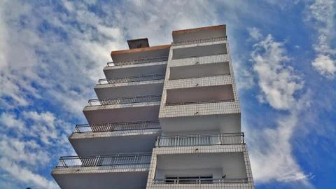 View from the bottom to the top of a multi-storey building against a blue sky Stock Photos