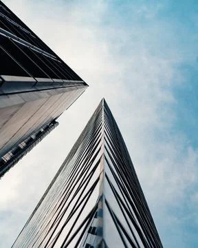 View from the bottom to the top of two large buildings with blue sky as backg Stock Photos