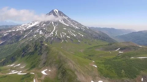 View from the bottom up to the volcano. The frozen river with snow and grass Stock Footage 72682770