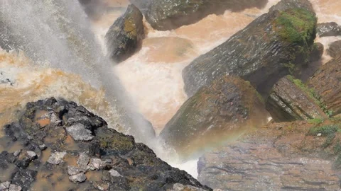 A view on the bottom of waterfall with gigantic rocks and flowing orange water. Video stock 141780586