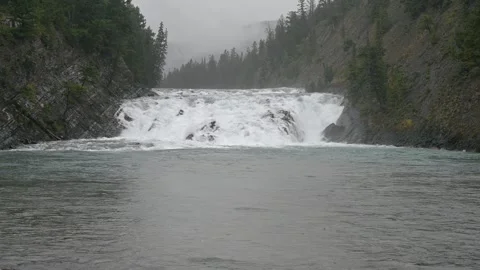 View of Bow Falls at Banff with water tumbling over waterfall under gray sky Stock Footage 306478720