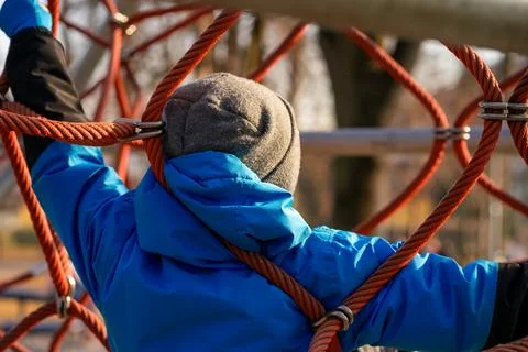 View of a boy in a blue jacket on the ropes at the playground Foto stock