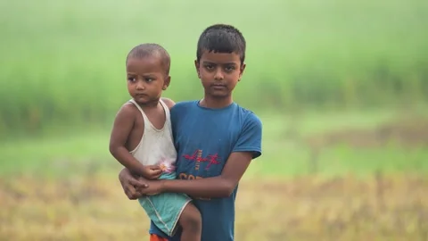 View of a boy carrying his younger brother in a field, Bangladesh. Video stock 335584434