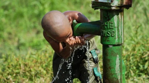 View of a boy drinking water from a hand pump, Bangladesh. Video stock 335584040
