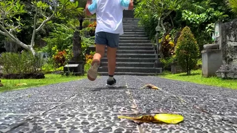 A view of a boy running along the road to a high staircase leading to an Stock Footage 267788147