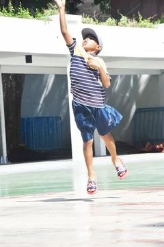 The view of a boy wearing a hat jumping and throwing a basketball Stock Photos