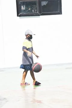 The view of a boy wearing a hat playing a basketball Stock Photos