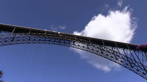View of bridge and sky and jumper with multi-colored parachute Stock Footage 8850772