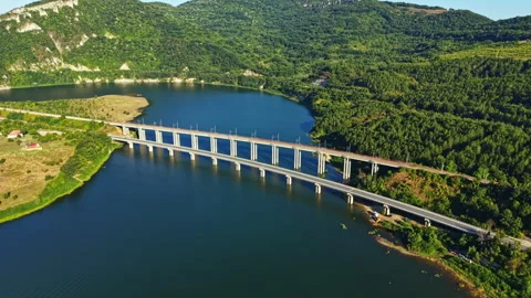 View of a bridge over a river with green hills in the background on a sunny day Stock Footage 341614258