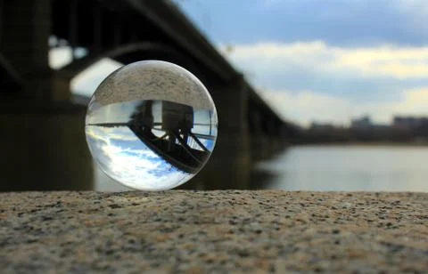 View of the bridge over the river through a glass ball. Stock Photos