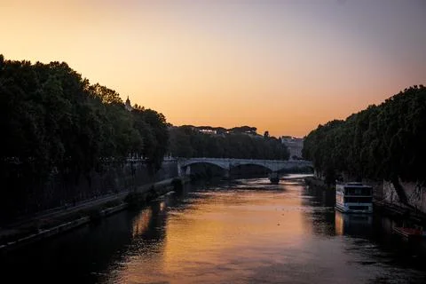 View of bridge over Tiber river with trees along on a cloudless evening sky Stock Photos