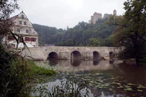 View of bridge over Wornitz River with castle in misty background Stock Photos