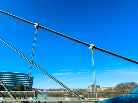 View of a bridge structure with cables and a clear blue sky during the day .. Stock Photos