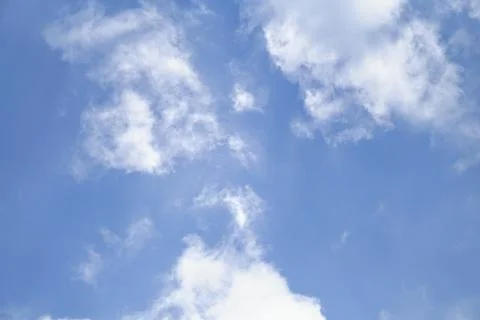 View of bright blue sky with soft white cumulus cloud formations during daytime. Stock Photos