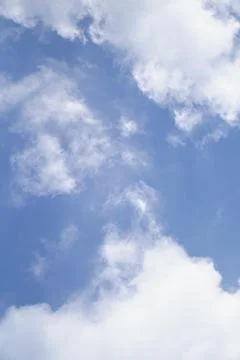View of bright blue sky with soft white cumulus cloud formations during daytime. Stock Photos