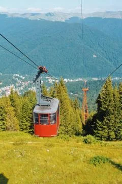 A view to bright red cableway cabin moving to the top of the mountain over th Stock Photos