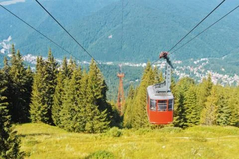 A view to bright red cableway cabin moving to the top of the mountain over th Stock Photos
