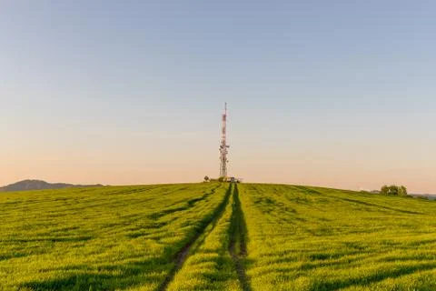 View of a broadcasting tower lying on a hill in the middle of a landscape in  Photos