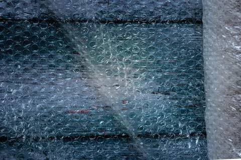 View of bubble wrap and roll over a wooden background Stock Photos