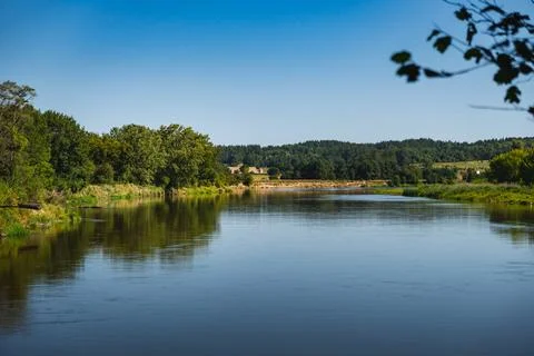 A view of the Bug River with its banks reflected in the water during the summ Stock Photos