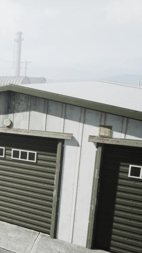 View of a building with two garage doors during the daytime near hills Stock Footage 338000925