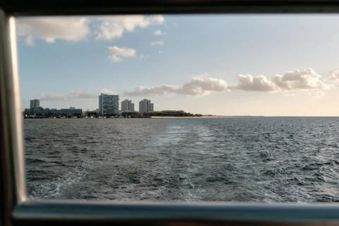 View of a built up peninsular with a sandy beach and harbour from a ferry Stock Photos