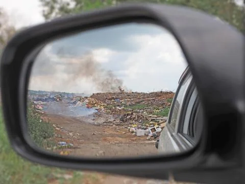 View of a burning garbage dump through a car mirror Stock Photos
