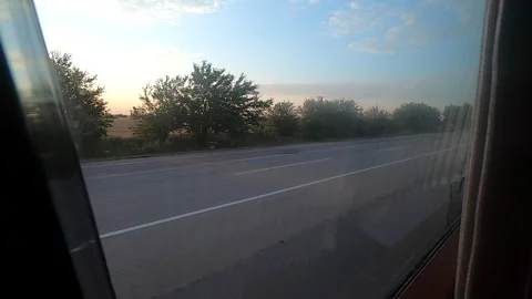 View from bus window View fields trees blue sky road cars moving bus Stock Footage 240574692