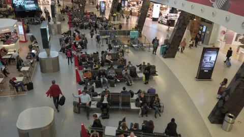 View of a busy airport interior coming down from an escalator Stock Footage