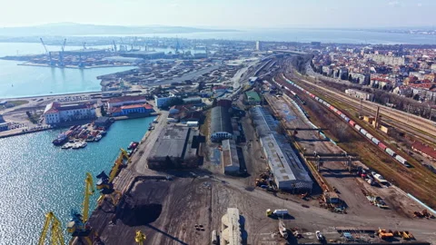 View of a busy port area with cranes, warehouses, and rail tracks during the Stock Footage 331064213