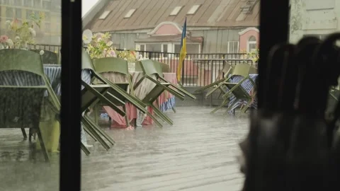 View of a cafe terrace during heavy rain. Wet tables and tablecloths decorated Stock Footage 318064337
