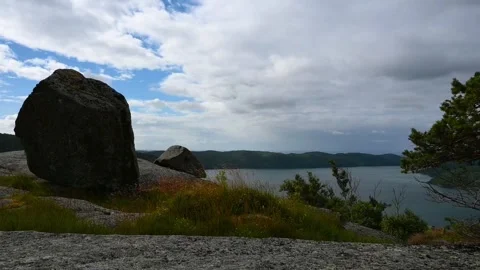 View of a calm lake and cloudy sky from a rocky hilltop in Norway on a summ.. Stock Footage 340213342