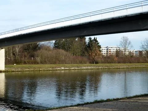 A view of a calm river under a small modern bridge Stock Photos