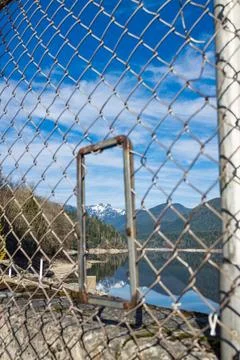 View of Capilano Reservoir through security fence gate with snow-capped mou.. Stock Photos