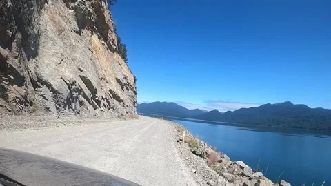 View from a car driving close to edge along river on a unpaved road in Patagonia Vidéo 130606796