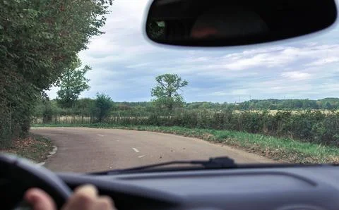 View from car inside driving on winding country road through windshield Stock Photos