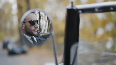 View in the car mirror of handsome driver in sunglasses Stock Footage 124731367