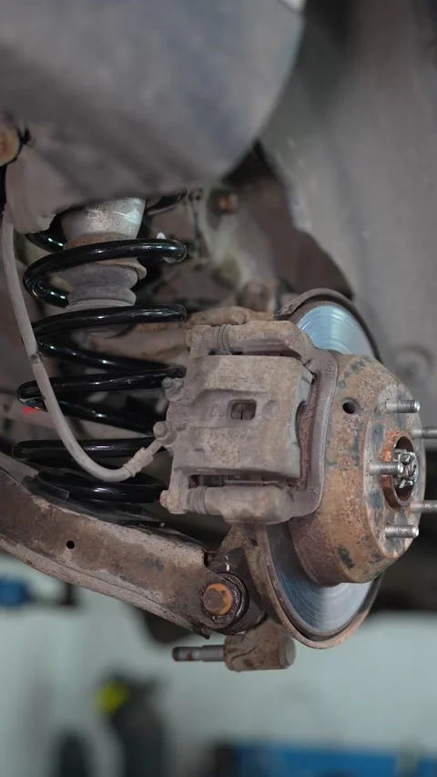 View of car rear brake disc caliper and suspension assembly on lift. Stock Footage 345912544