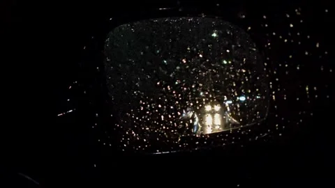 View of a car in the rear-view mirror from behind. Nighttime road in the rain Stock Footage 336391618