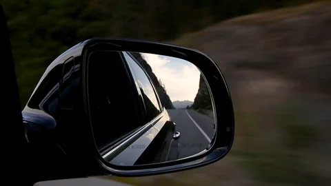 View of a car side view mirror of a mountain forest highway with a forest and Stock Footage 111449290