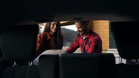 View from car of smiling happy young couple which unloading the trunk from boxes Video stock 121664882