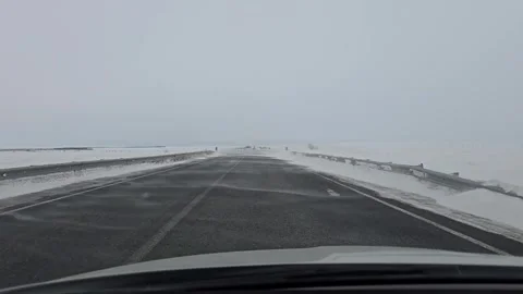 A view from a car onto a snow-covered road during strong winds and snowdrifts Stock Footage 330274957