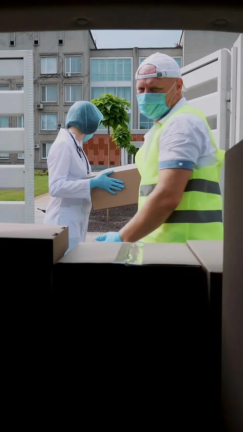 View from car trunk: Courier, in protective mask, gloves, unloading and handing Stock Footage 317309089