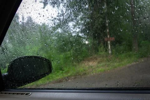 View from the car window in the rain through glass with water drops Stock Photos